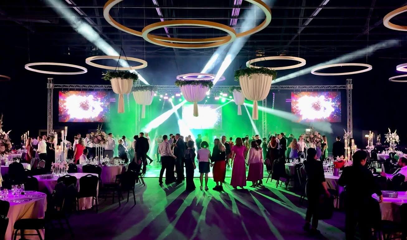 Sala de evenimente cu decor suspendat, ecrane LED și lumini verzi pe ringul de dans